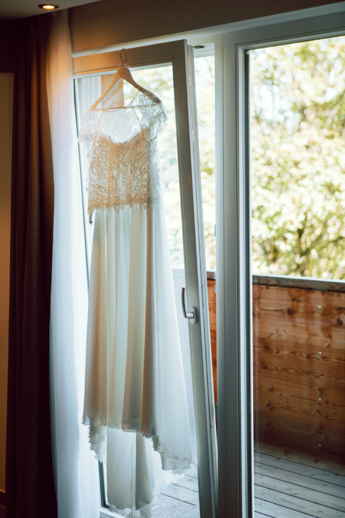 Brautkleid hängt am Fenster mit Blick auf die Berge