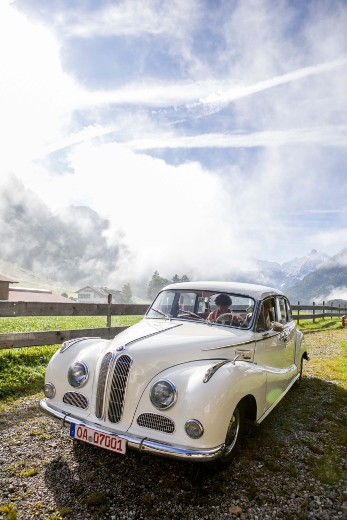Oldtimer-Hochzeitsauto vor nebelverhangenen Bergen am Kühberg